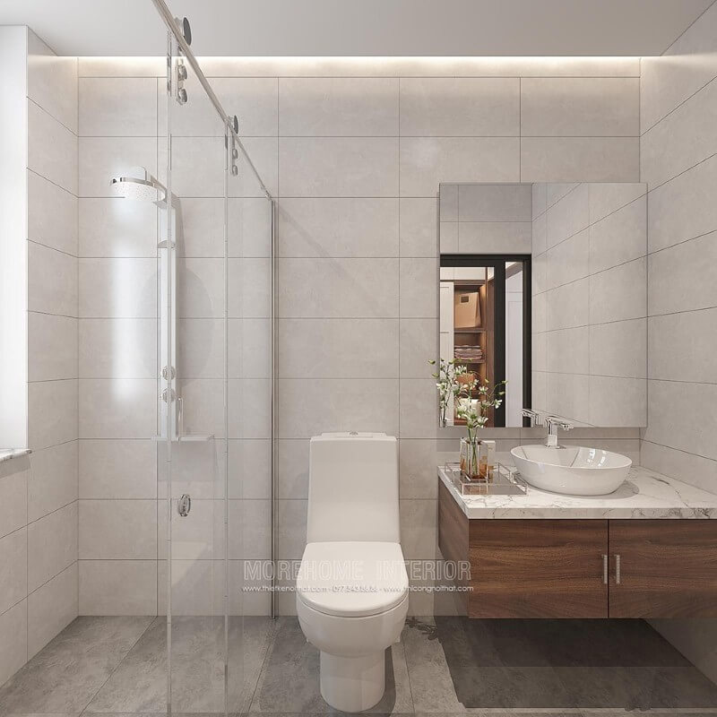 Thiết kế phòng tắm chung cư theo phong cách hiện đại đẹp với cách lựa chọn đồ vật tinh gọn nhưng lại tạo vẻ đẹp sang trọng cuốn hút từ tường ốp gạch giả bê tông, gương không khung ốp tường, phòng tắm kính cửa trượt.